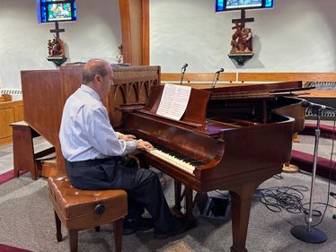 Stephen Toney, Queen of the World Parish Music Director, playing the piano repaired thanks to a Michael C. McCloskey Memorial Grant.
