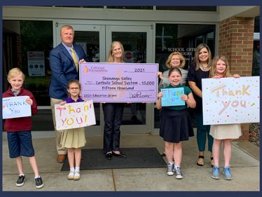 Lisa Louis, Executive Director, & Ruthanne Beighley, Board Chair, join Bill Blum, Director of Finance, Katie Tiefenthal, Principal, and Saint John Paul II Elementary School students to celebrate their Education grant.