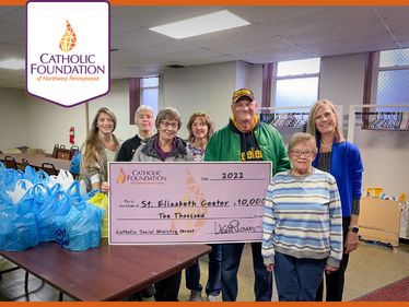 Lisa Louis, Foundation Executive Director, far right, presents grant check to Jessica Struthers, Saint Elizabeth Center CEO, far left, along with volunteers on a busy day of distributing food.